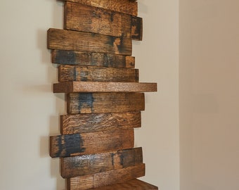 Peut inclure: Une étagère murale composée de planches de bois de récupération horizontales avec une finition brun foncé. La structure présente des planches décalées et saillantes créant plusieurs surfaces planes, mettant en valeur le grain naturel du bois et des marques carbonisées.