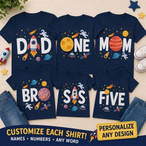 May include: A set of six navy blue t-shirts featuring space-themed graphics with white text. The shirts display various designs including rockets, planets, astronauts, and stars, with words such as DAD, ONE, MOM, BRO, SIS, and FIVE printed on them.