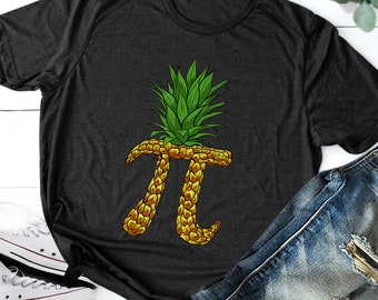 May include: A dark grey t-shirt featuring a pineapple design shaped like the mathematical symbol pi. The pineapple is yellow and green.