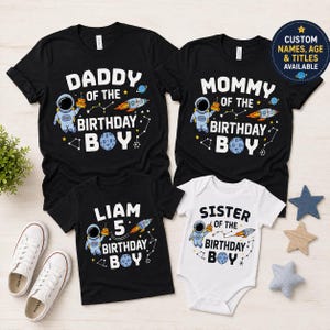 May include: Three black t-shirts and one white baby bodysuit featuring space-themed graphics. The designs include an astronaut, a rocket, a planet, and stars with text reading Daddy, Mommy, Liam 5, and Sister of the Birthday Boy.