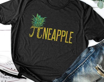 May include: A dark grey t-shirt with a yellow and green pineapple graphic and the text "Pi-neapple".