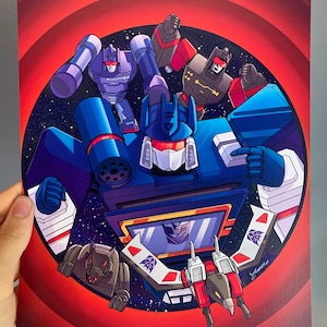 May include: A colourful illustration featuring Soundwave and other robotic characters from the Transformers series set against a dark starry background within a circular frame, surrounded by a red concentric ring pattern on a rectangular print.