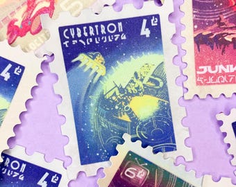 May include: A collection of postage stamps with a science fiction theme. The stamps feature colorful illustrations of space scenes, robots, and the word "CYBERTRON". The stamps have a perforated edge and are arranged on a light purple surface.