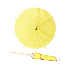 May include: A yellow paper cocktail umbrella with a wooden stick. The umbrella is closed and has a red rubber band around the stick.