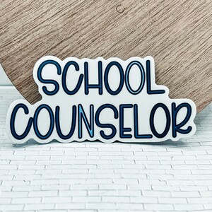May include: A white sticker with blue outline lettering that reads "SCHOOL COUNSELOR".
