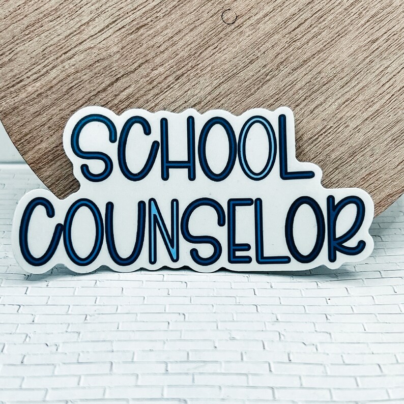 May include: A white sticker with blue outline lettering that reads "SCHOOL COUNSELOR".