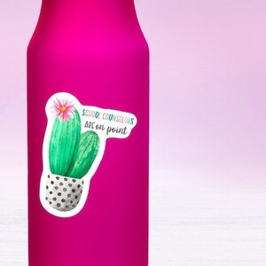 May include: A pink water bottle with a sticker of a cactus in a pot. The sticker says "School Counselors Are On Point".
