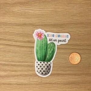 May include: A sticker with a green cactus in a black and white polka dot pot. The cactus has a pink flower on top and the text "School Counselors Are on Point" in rainbow colors.