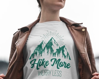 May include: White t-shirt with a green mountain graphic and the text "Hike More Worry Less".