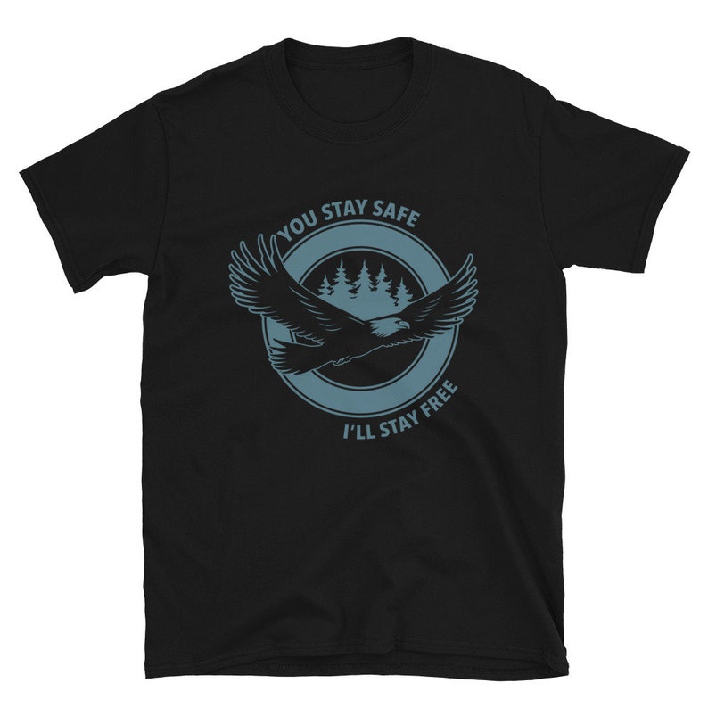 K&ouml;nnte beinhalten: Schwarzes T-Shirt mit einer blauen Grafik eines im Flug befindlichen Adlers mit dem Text "You Stay Safe I'll Stay Free" in einem Kreis darum.