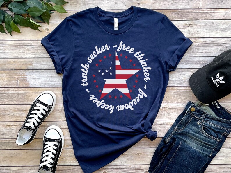 Puede incluir: Una camiseta azul marino con un dise&ntilde;o de estrella blanca y el texto "truth seeker - free thinker - freedom keeper".