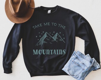 May include: Black sweatshirt with a graphic of mountains and stars. The text "Take me to the mountains" is printed on the sweatshirt.