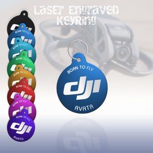 Peut inclure: Un porte-clés rond bleu avec le texte "Born to Fly" et le logo DJI, avec le mot "Avata" en dessous. Le porte-clés est gravé au laser et est disponible dans une variété de couleurs.