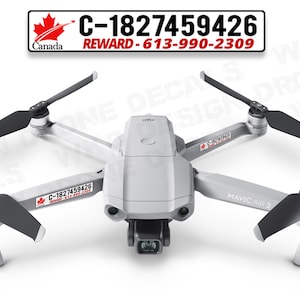 Può includere: Un drone bianco con eliche nere e una telecamera. Il drone ha un adesivo che dice "C-1827459426" e "REWARD-613-990-2309". Il drone è etichettato "MAVIC AIR 2".