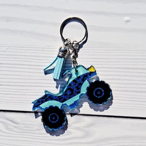 May include: A blue and black glitter keychain shaped like an ATV with a silver tassel.
