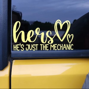 May include: A yellow vinyl decal with the words "hers" and a heart, followed by the text "He's just the mechanic".