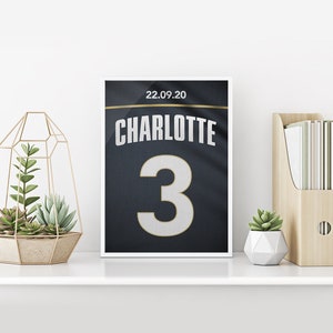 May include: A framed print of a black and gold jersey with the name "CHARLOTTE" and the number "3" on it. The date "22.09.20" is printed above the name.
