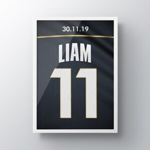 May include: A framed black and white jersey with the name "Liam" and the number "11" in white with gold trim. The date "30.11.19" is printed in gold at the top.
