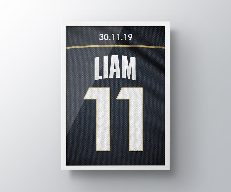 May include: A framed black and white jersey with the name "Liam" and the number "11" in white with gold trim. The date "30.11.19" is printed in gold at the top.