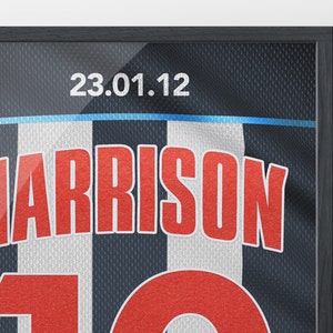 May include: A framed black and white jersey with the name "HARRISON" and the number "10" in red. The date "23.01.12" is printed at the top of the jersey.