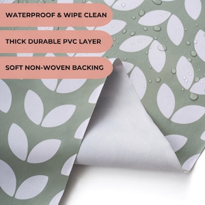 May include: Close-up of a green and white patterned fabric. The fabric features a repeating leaf design in white against a green background. The text on the image reads: "WATERPROOF & WIPE CLEAN", "THICK DURABLE PVC LAYER", and "SOFT NON-WOVEN BACKING".