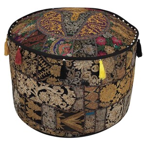 Pode incluir: Puff redondo de patchwork com base preta e bordados dourados intrincados. O topo apresenta um design circular com padrões florais e geométricos em tons de dourado, roxo e verde. As laterais são adornadas com borlas de várias cores.