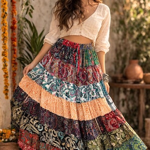 May include: A vibrant, tiered maxi skirt featuring a patchwork of paisley and floral prints. The skirt, with a drawstring waist, is worn with a cream-coloured, button-down crop top. The skirt's colours include red, blue, green, orange, and black.