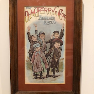 May include: Framed vintage advertisement for O.M. Ferry & Co. Standard Seeds. The artwork features a group of children with their arms raised. The frame is a dark brown wood with a reddish-brown matting.