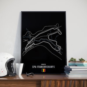以下が含まれることがあります： スパ・フランコルシャンサーキットの白い線画が描かれた、黒いフレームのプリント。テキスト「CIRCUIT DE SPA-FRANCORCHAMPS」は白で表示され、小さなベルギーの国旗が付いています。白いヘルメットと模型飛行機が見えます。