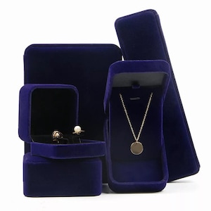 Peut inclure: Quatre bo&icirc;tes &agrave; bijoux en velours bleu. Une bo&icirc;te est carr&eacute;e et comporte deux compartiments pour des boucles d'oreilles. Une autre bo&icirc;te est carr&eacute;e et comporte un seul compartiment. La troisi&egrave;me bo&icirc;te est rectangulaire et comporte un seul compartiment pour un collier. La quatri&egrave;me bo&icirc;te est longue et rectangulaire.