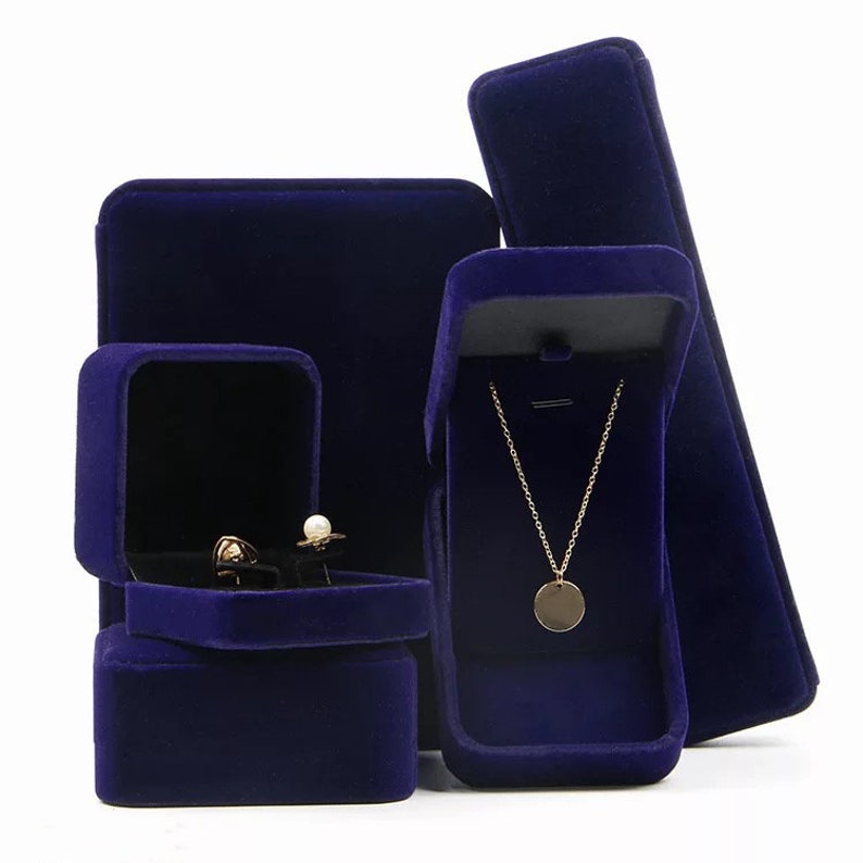 Peut inclure: Quatre bo&icirc;tes &agrave; bijoux en velours bleu. Une bo&icirc;te est carr&eacute;e et comporte deux compartiments pour des boucles d'oreilles. Une autre bo&icirc;te est carr&eacute;e et comporte un seul compartiment. La troisi&egrave;me bo&icirc;te est rectangulaire et comporte un seul compartiment pour un collier. La quatri&egrave;me bo&icirc;te est longue et rectangulaire.