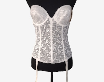 May include: White lace strapless corset with a floral pattern and adjustable straps. The corset has a boned structure and is designed to provide support and shape.