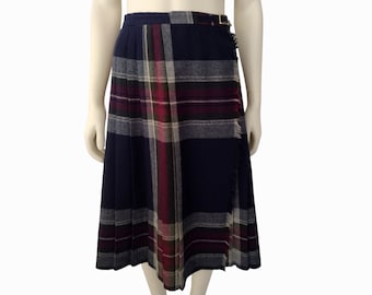 May include: A navy blue plaid skirt with a red, white, and gray plaid pattern. The skirt has a wrap-around design and a belt with a gold buckle.