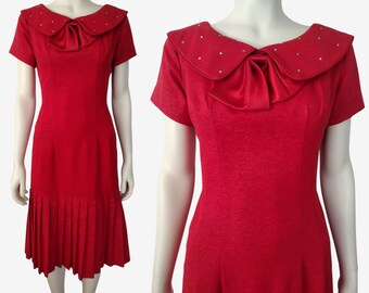 May include: A red dress with a large, white, satin bow at the neckline. The collar is trimmed with small, white rhinestones. The dress has short sleeves and a pleated skirt.