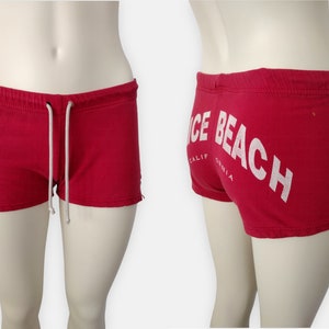 May include: Red athletic shorts with white trim and "Nice Beach California" printed on the back.