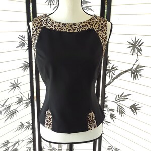 May include: A sleeveless black top with a leopard print trim around the neckline and sides.