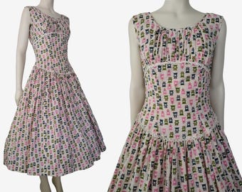 May include: A white sleeveless dress with a pink, green, and blue geometric pattern. The dress has a fitted bodice and a full skirt.
