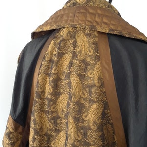 Peut inclure: Une veste noire et marron avec un motif paisley au dos. La veste a un col montant et une doublure matelass&eacute;e.