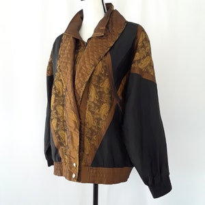 Peut inclure: Une veste noire et dor&eacute;e &agrave; motif paisley. La veste a une fermeture &eacute;clair et un col montant.