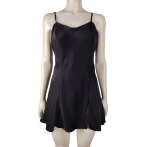 May include: A black slip dress with thin spaghetti straps and a sweetheart neckline. The dress has a fitted bodice and a flared skirt with a side slit. The dress is made of a smooth, shiny fabric.