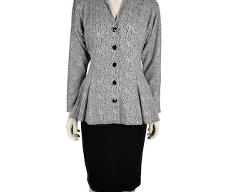May include: A two-piece suit featuring a black and white patterned jacket and a black skirt. The jacket has a V-neck, long sleeves, and black buttons. The skirt is knee-length. The suit is displayed on a mannequin.