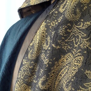 Peut inclure: Une robe &agrave; capuche bleu fonc&eacute; avec un motif paisley dor&eacute;. La robe est bord&eacute;e d'une garniture brune.