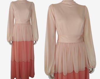 May include: A long-sleeved, tiered maxi dress in shades of pink and peach. The dress has a high neckline and a fitted bodice. The skirt is made of a sheer fabric and has a scalloped hem.