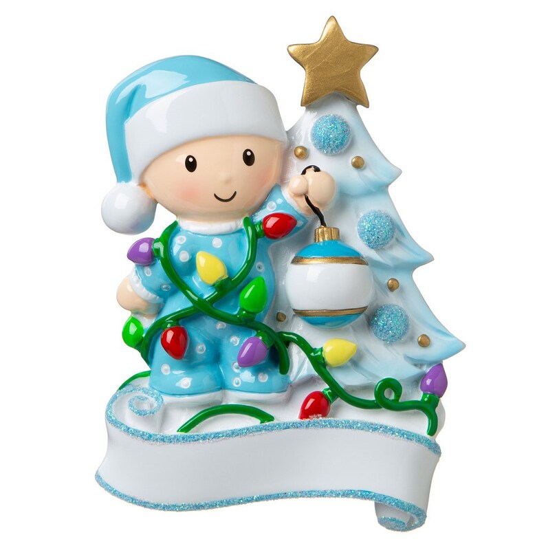 May include: A blue and white Christmas ornament featuring a baby in pajamas holding a Christmas tree ornament. The baby is surrounded by a string of Christmas lights. The ornament has a blank banner for personalization.
