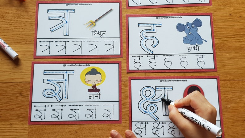 May include: Four white cards with red borders, each featuring a different Hindi letter with a blue outline. The letters are 'त्र', 'ज्ञ', 'ह', and 'क्ष'. Each card also includes a picture and the Hindi word for the letter. The cards are designed for learning Hindi.