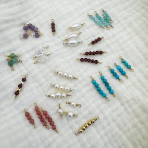 May include: Assortment of jewelry making supplies including beads, pearls, and connectors. The beads are in various colors including turquoise, purple, red, and green. The pearls are white. The connectors are gold.