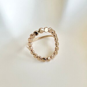 May include: A gold ring with a circle design made of small, round beads.