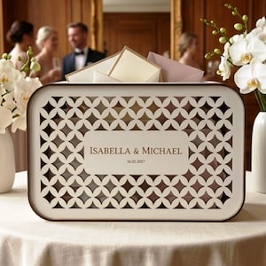 May include: An off-white rectangular wedding card box with a geometric design and a dark brown trim. The box is personalised with the names "ISABELLA & MICHAEL" and the date "10.25.2027".