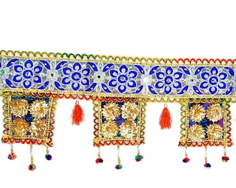 May include: A colorful door hanging with a blue and gold patterned band and square tassels. The tassels are decorated with beads and have orange fringe.