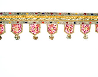 May include: A gold and red decorative door hanging with tassels. The hanging has a white background with a geometric pattern in red, yellow, and orange.